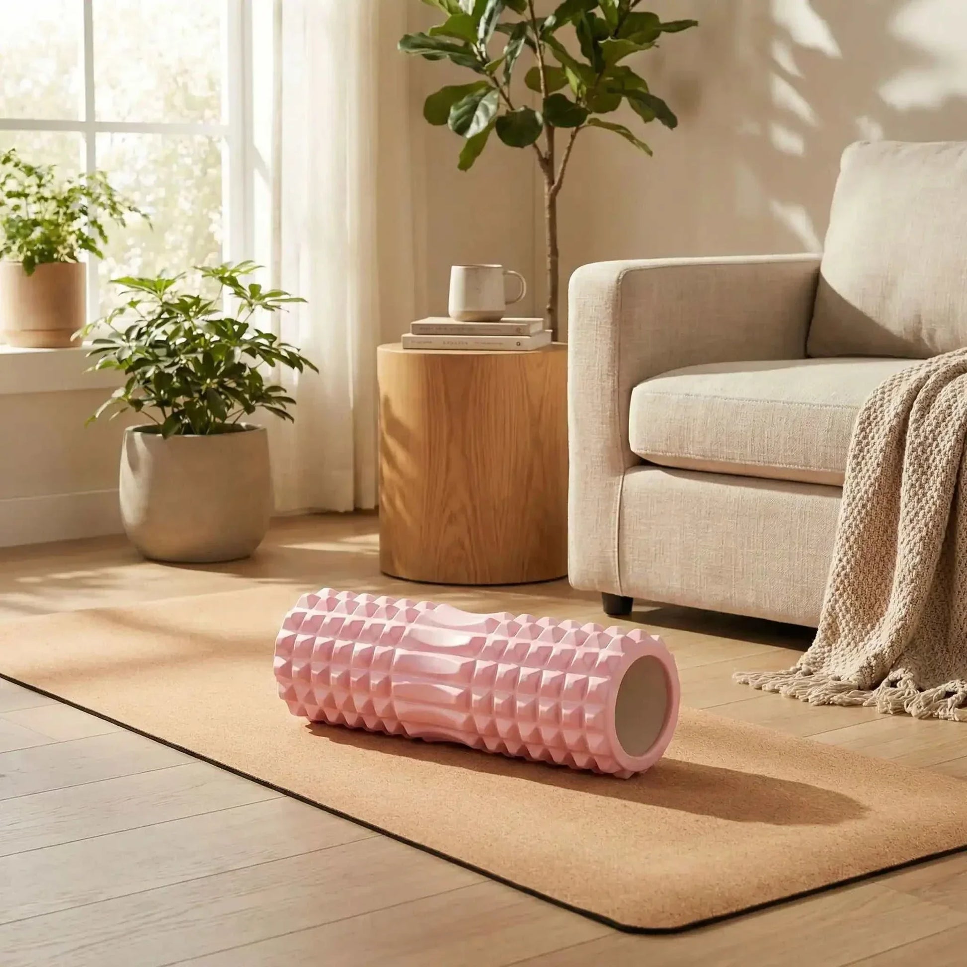 rouleau de massage rose sur tapis de yoga sallon plantes
